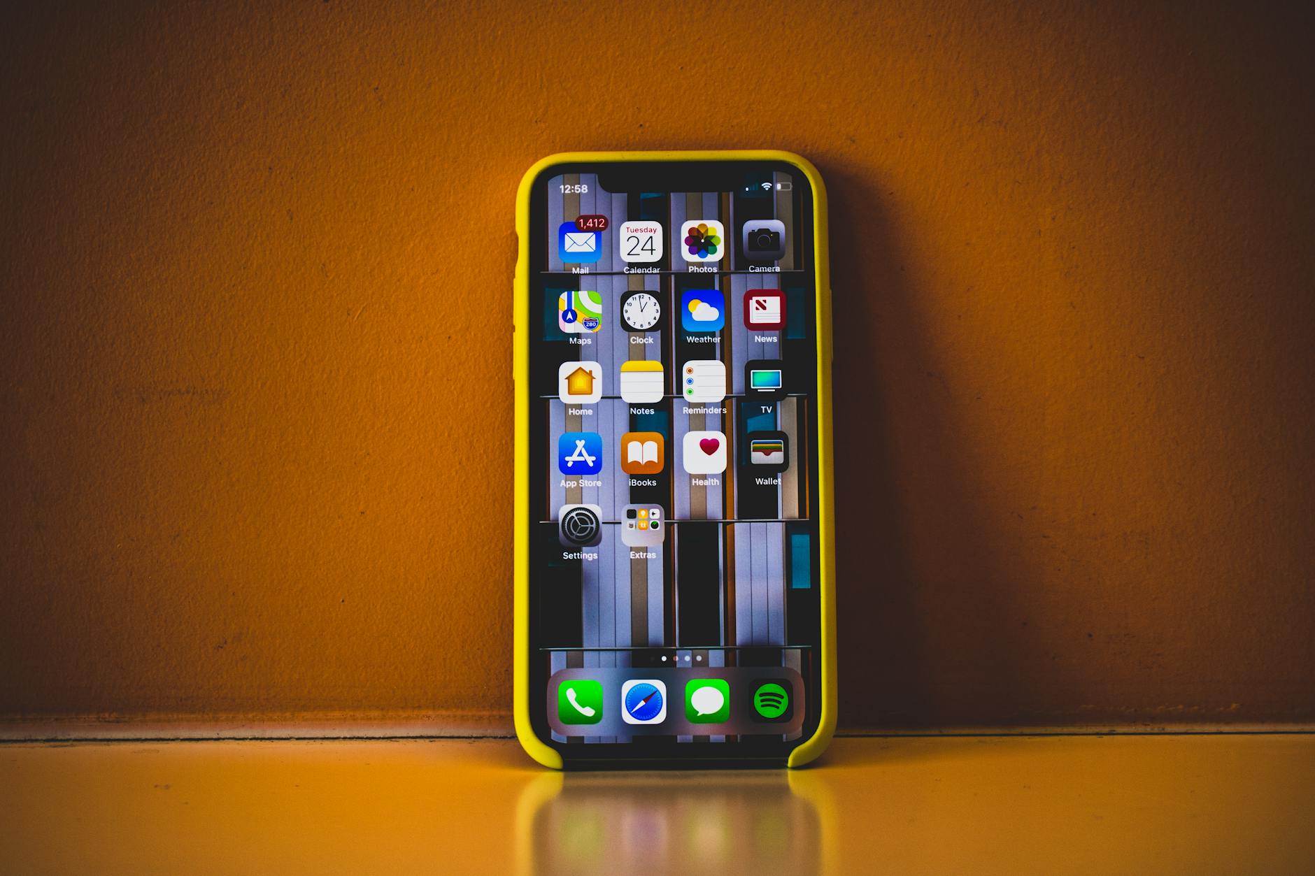 A smartphone with a yellow case showing various app icons on its screen.