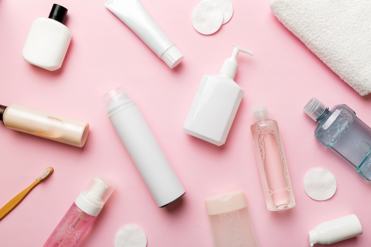 Various skincare products including lotions and cleansers on a pink surface